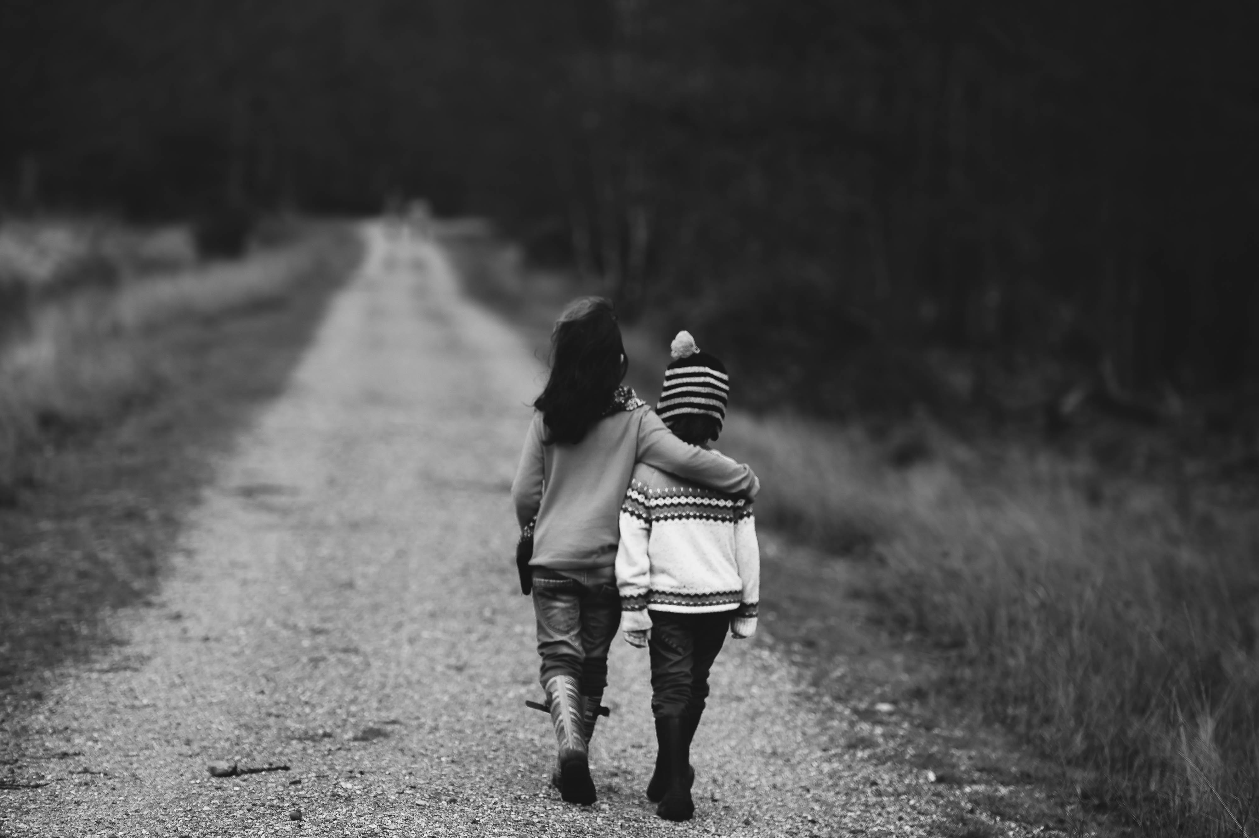 Two children walking with hand around the other